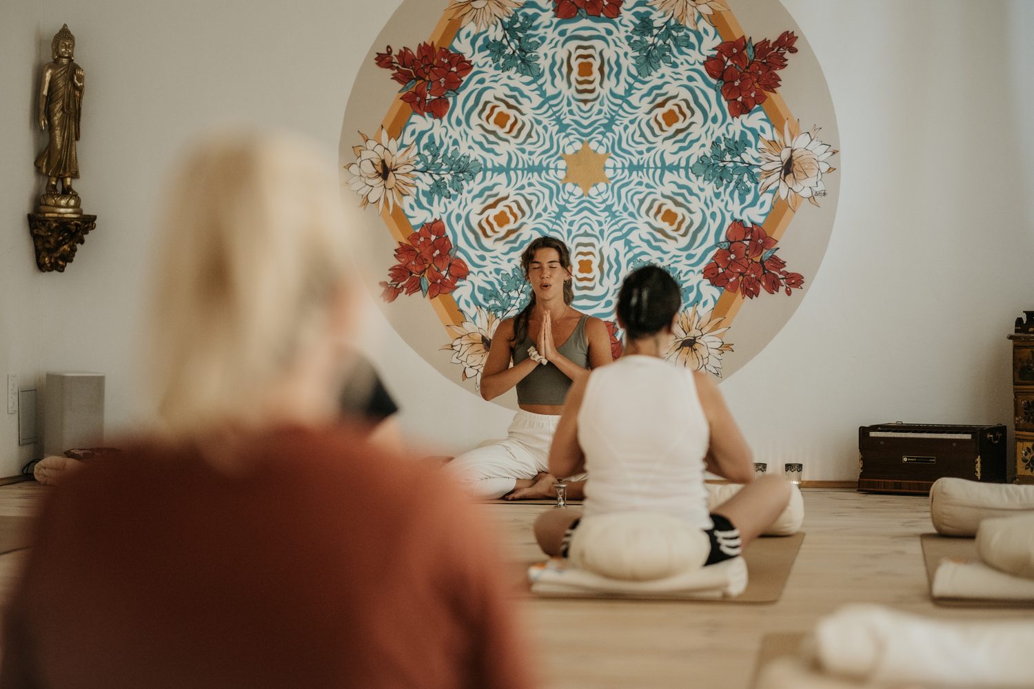Frau leitet eine Yogastunde vor einem Mandala – Raum, um wieder zu träumen